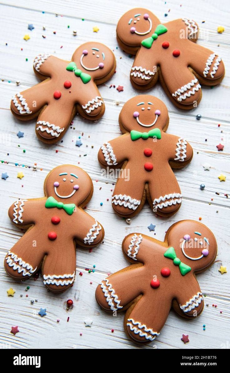 ginger cookies decorated with icing and sprinkles on a white wooden table - stock image