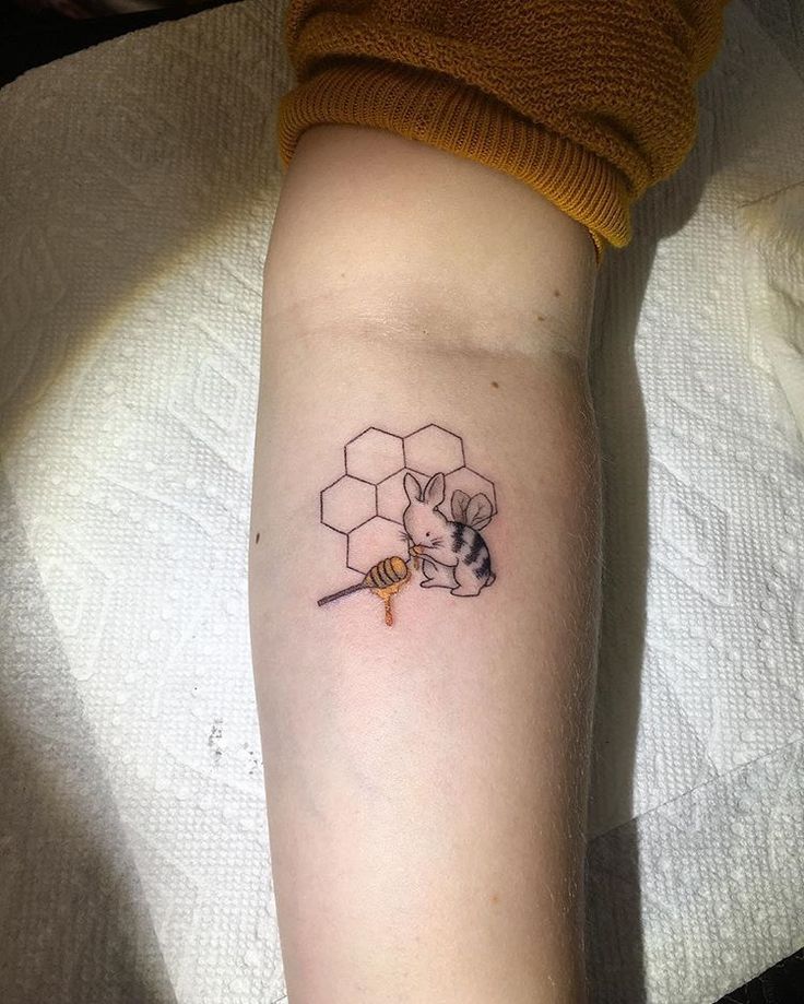 a person with a bee and honey tattoo on their arm