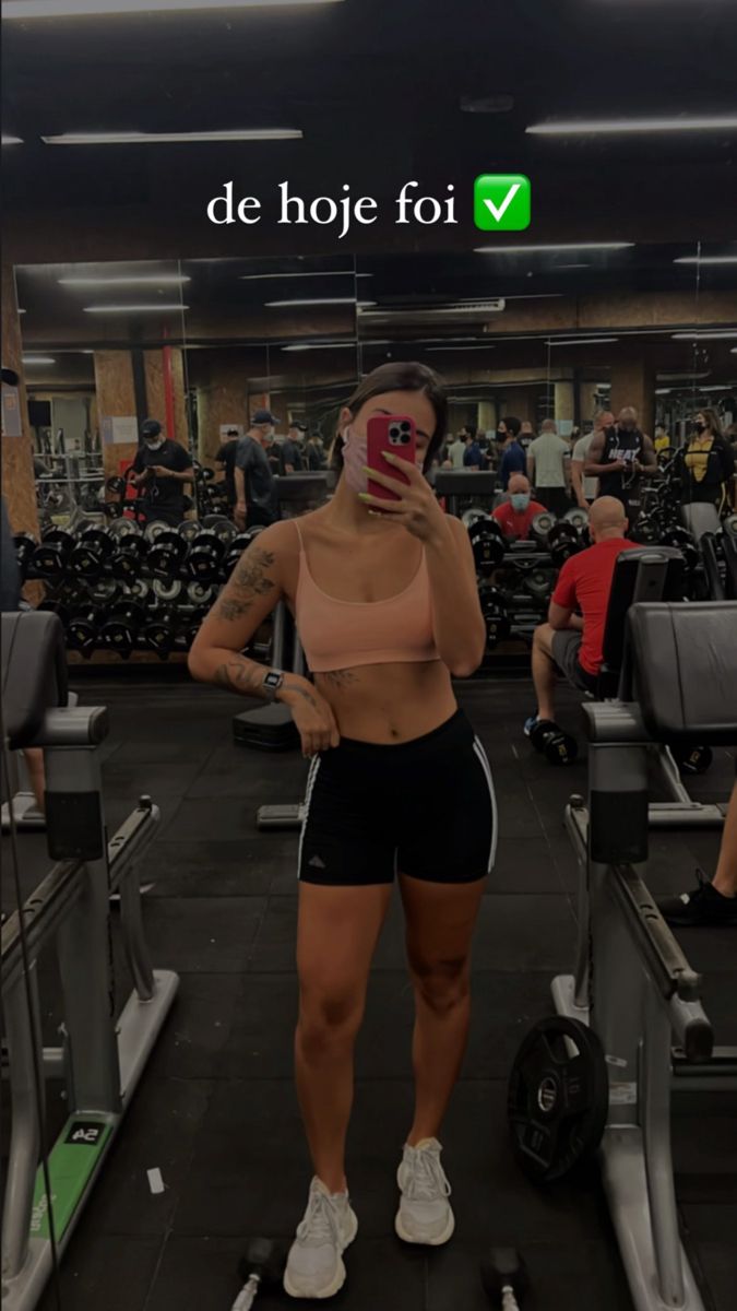 a woman wearing a face mask standing on a treadmill in the middle of a gym