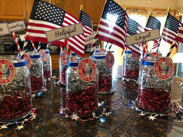 there are many patriotic flags in jars on the counter top with name tags attached to them