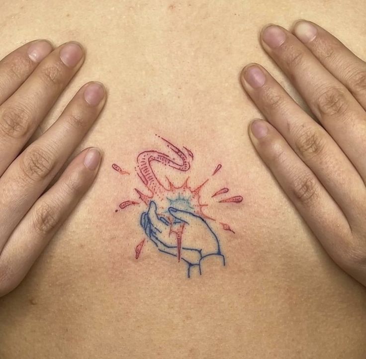 two hands holding up a tattoo on the back of a woman's chest