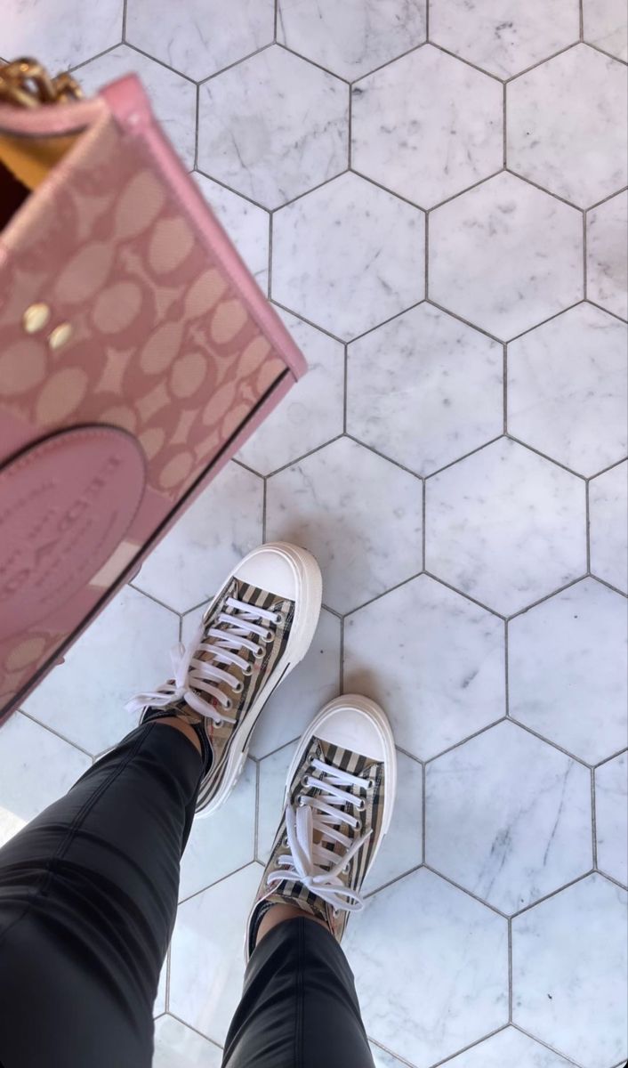 a person standing in front of a pink bag on top of a tiled floor with their feet up