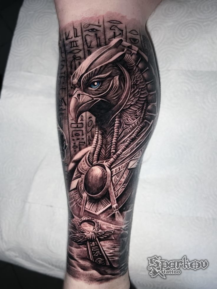 an arm with a black and grey tattoo on it, depicting the head of a bird