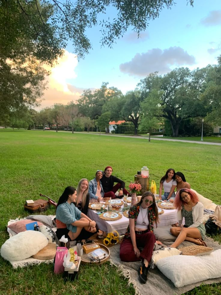 a group of people sitting on top of a grass covered field next to each other