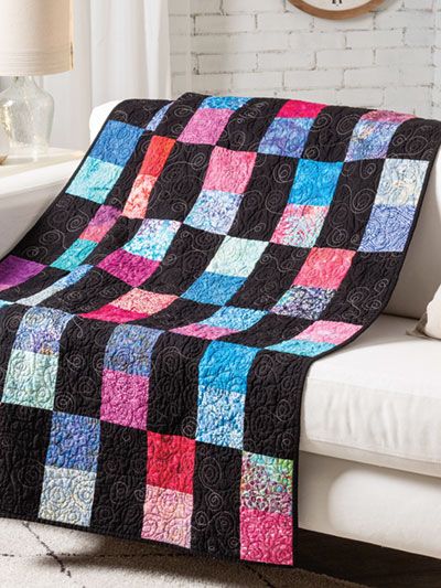 a white couch with a black and pink quilt on it