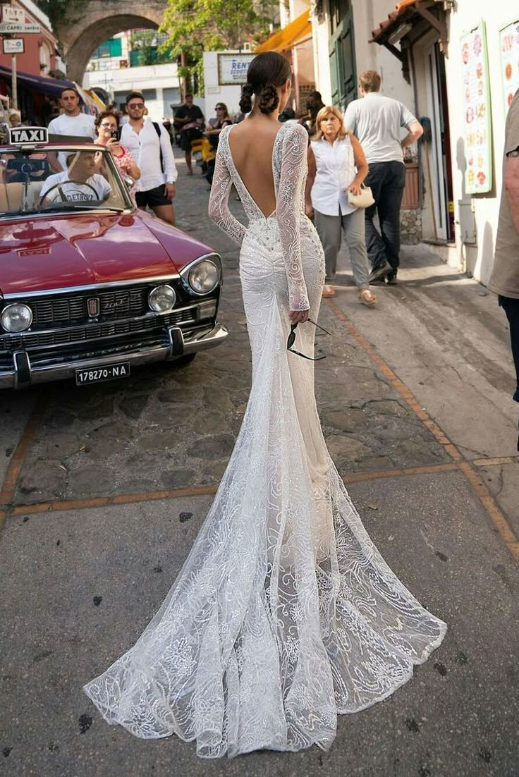 a woman in a white dress is walking down the street with her back to the camera