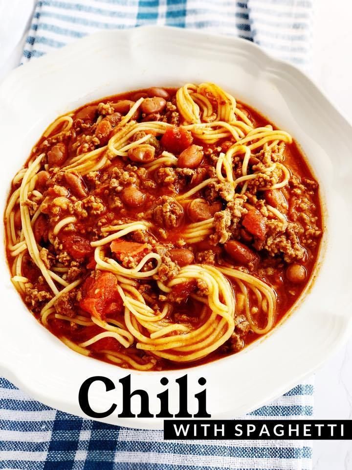 a white bowl filled with spaghetti and meat on top of a blue and white table cloth