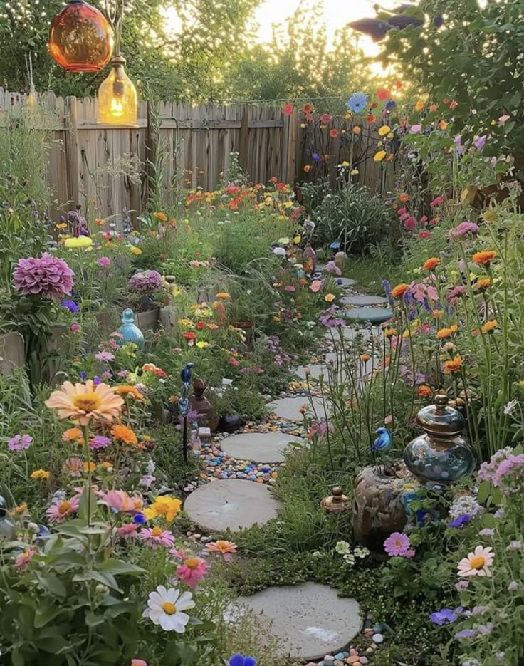 a garden filled with lots of flowers next to a wooden fence and some lights hanging from the ceiling