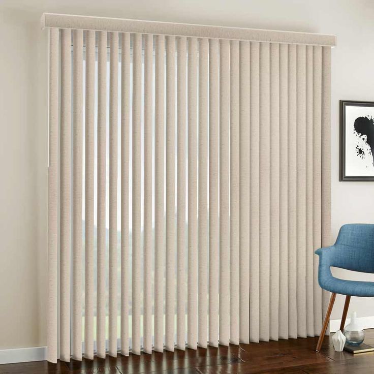 a living room with white vertical blinds in the window and a blue chair next to it