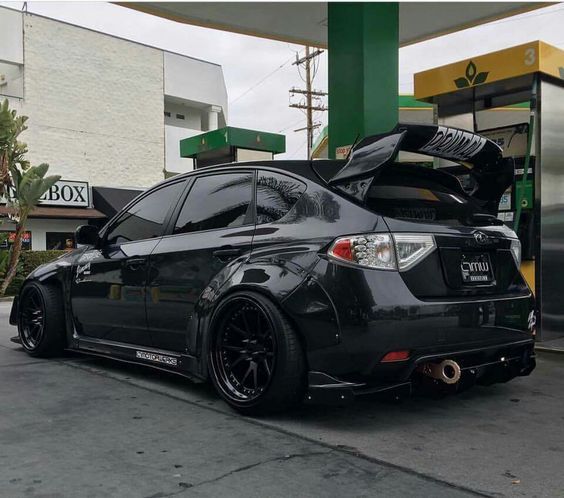 a black car parked in front of a gas station with it's hood open