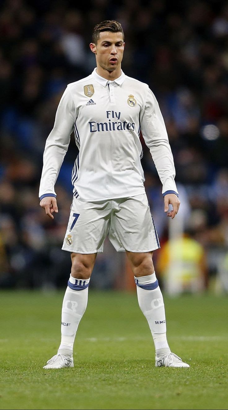 a man standing on top of a soccer field wearing a white uniform and blue socks