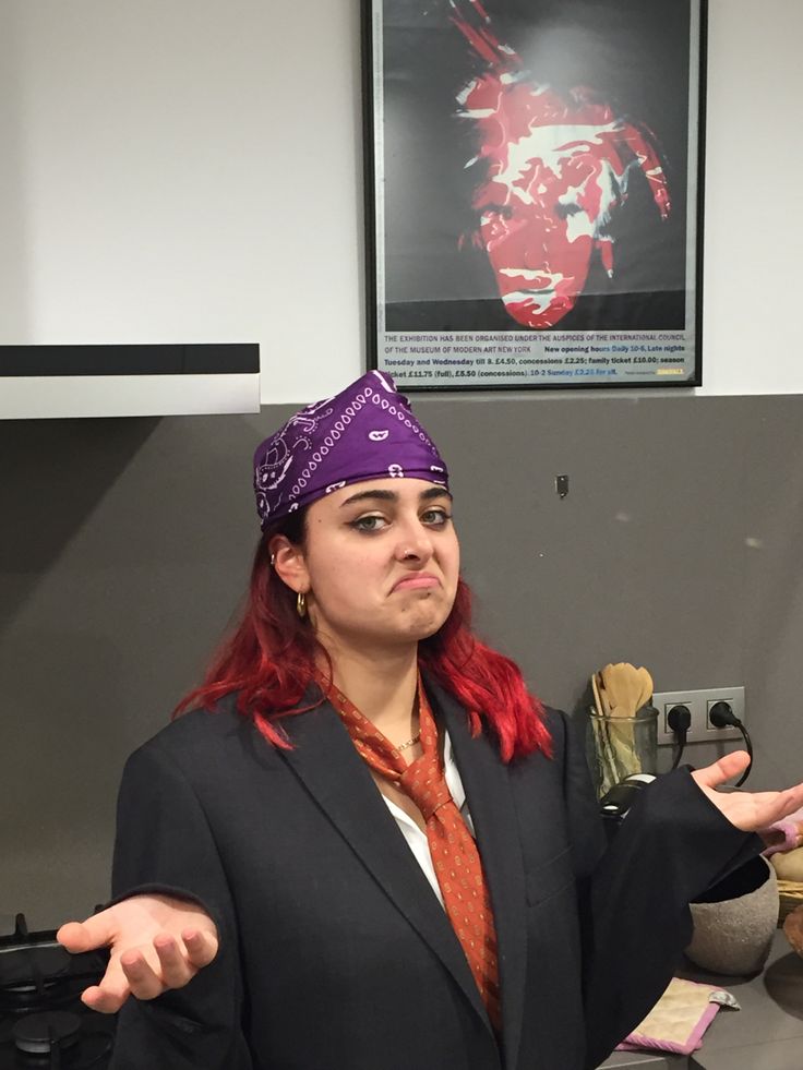 a woman with red hair wearing a purple bandana in an office cubicle area