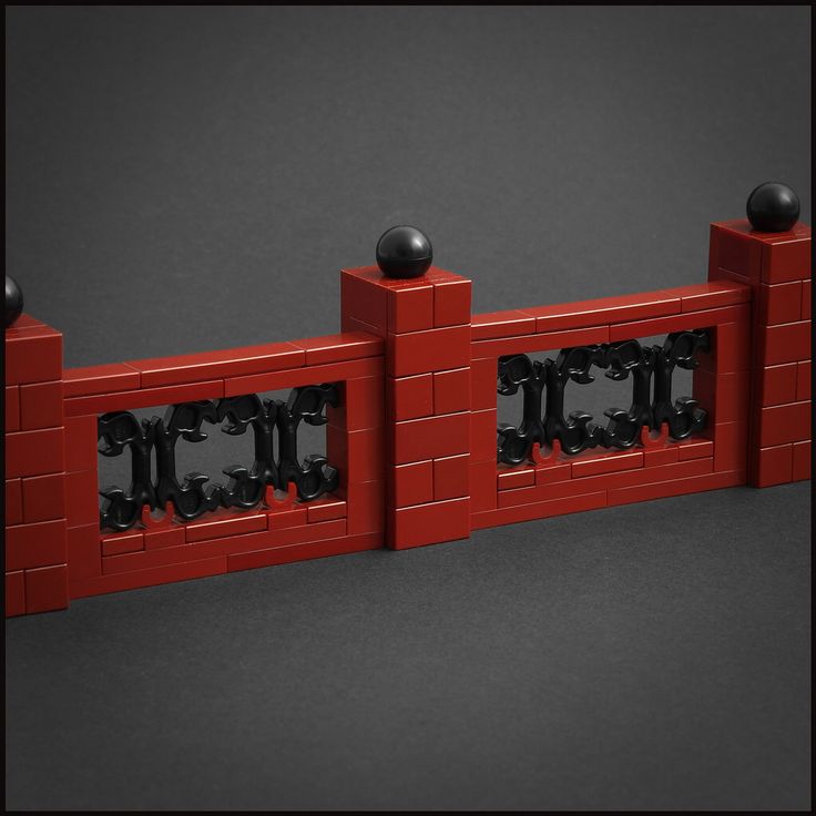 a red brick fence with black knobs on each side and two balls at the top