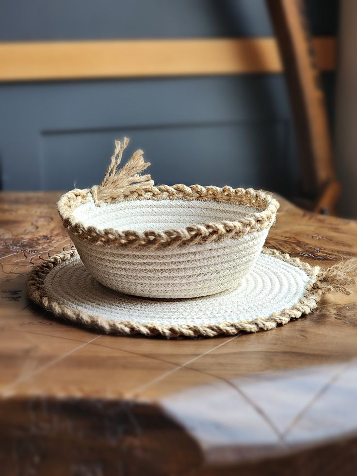 a white bowl sitting on top of a wooden table next to a plate with a straw hat