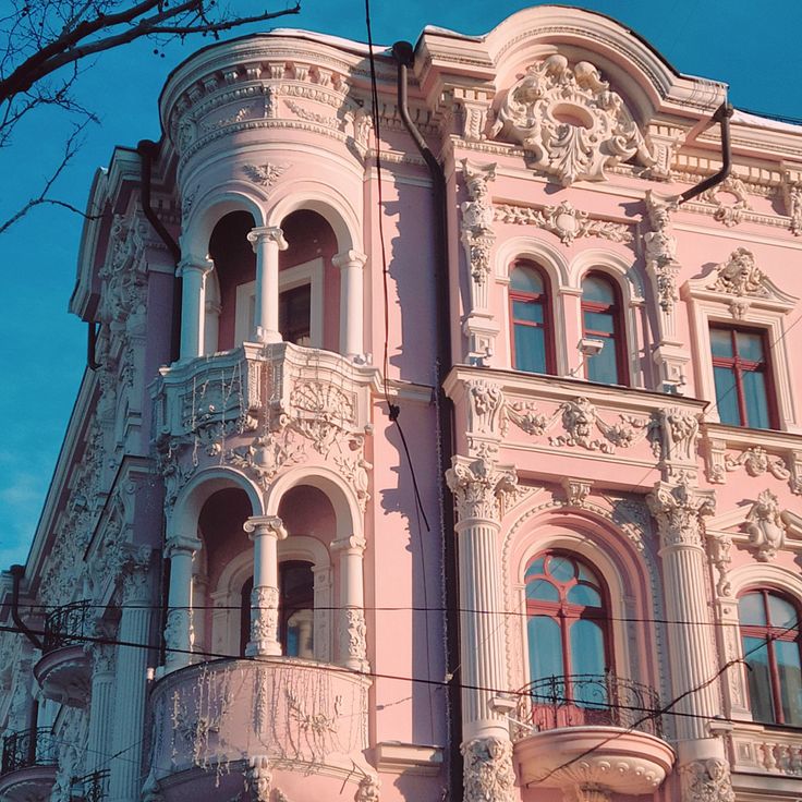 an old pink building with many windows and balconies on the front, against a blue sky