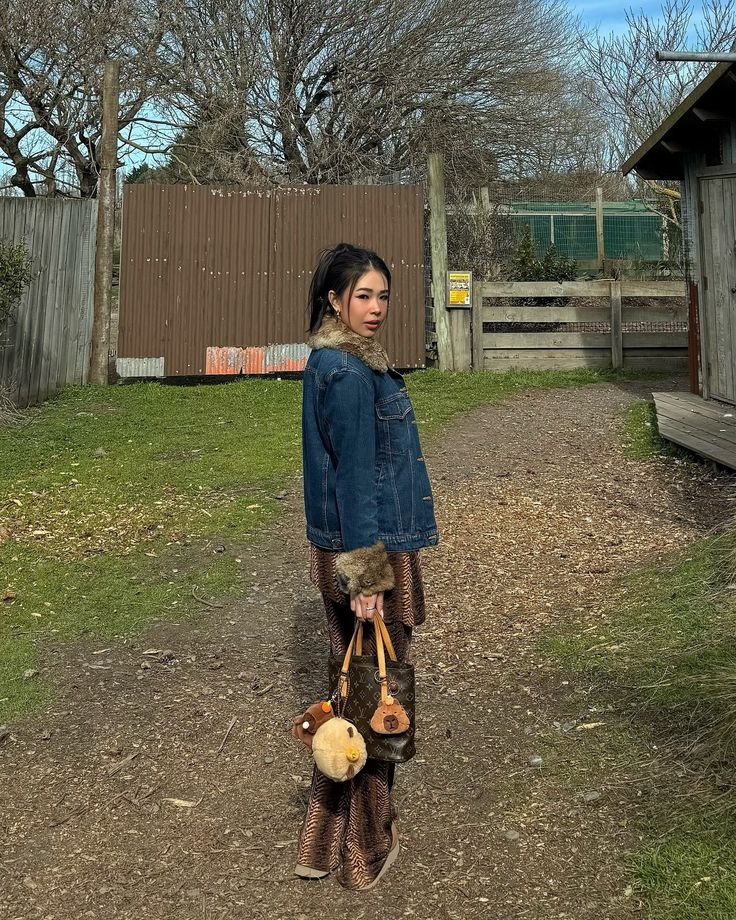 a woman is standing in the dirt with her handbag and teddy bear on it