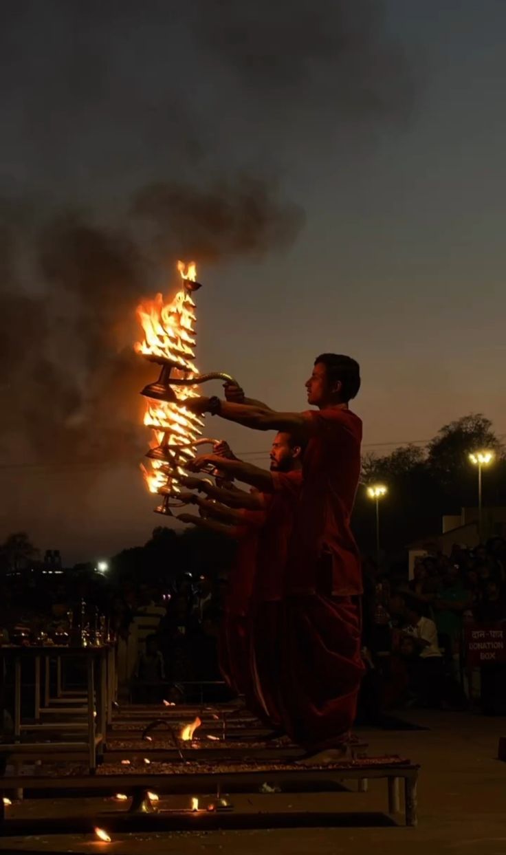 a man standing in front of a bunch of torches with flames coming out of it