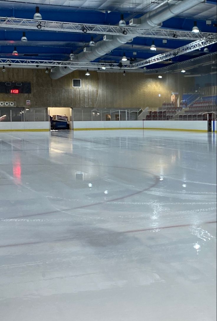 an empty ice rink with lights on the ceiling