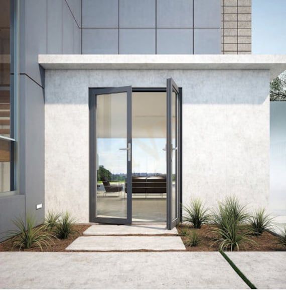 an open glass door leading to a patio area with plants and grass on the ground