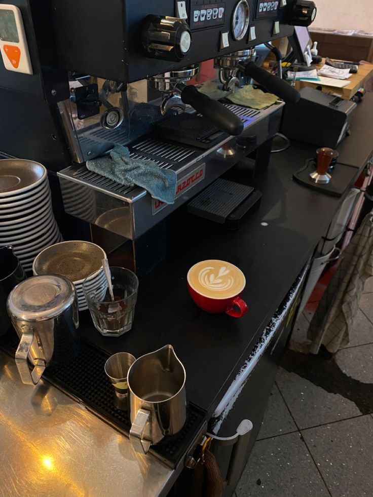 a coffee machine sitting on top of a counter filled with cups and saucer's