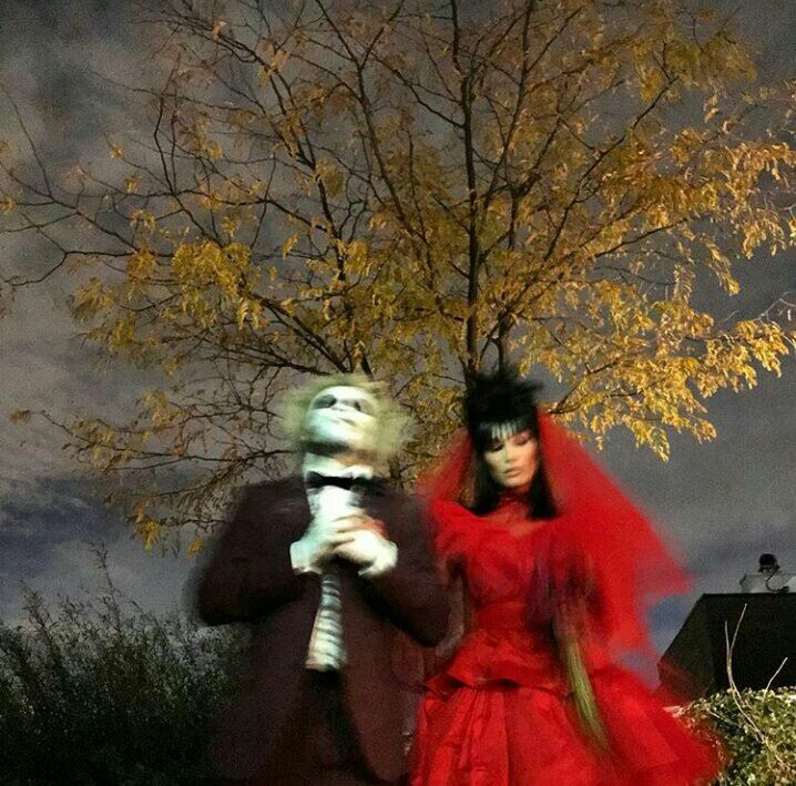 a man and woman dressed up in costumes standing next to each other under a tree