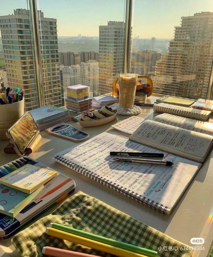 there are many papers and pens on the table in front of the large glass window