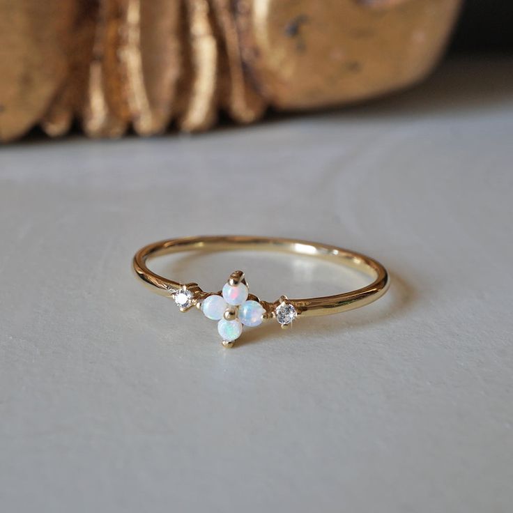 This dainty Forget Me Not ring features four natural Australian opal hugged between two natural diamonds. Set on a polished dainty band. A beautiful ring to wear on your finger to remind you of the beauty of life. Crafted in 14K solid gold in our NYC studio. 14K solid gold Natural Australian opals and diamonds 1.2mm ring band ** This item is specially made for you. Please allow 1-2 week lead time. Shipping:Domestic: Free standard shipping within the U.S.International: Free standard shipping for Forget Me Not Ring, Opal And Sapphire Ring, Simple Diamond Ring, Forget Me Not Flower, The Beauty Of Life, Dainty Band, Nyc Studio, Beauty Of Life, Birthday Wishlist