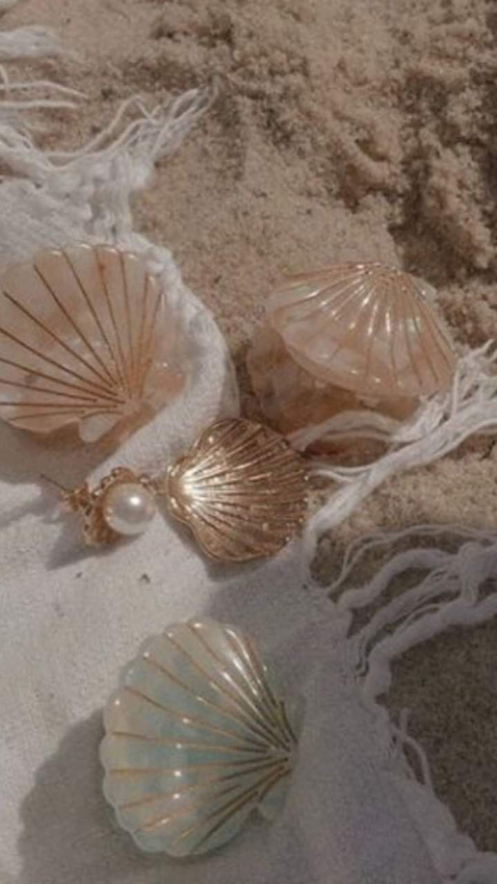 three seashells are laying on the sand with pearls in their shells and some tassels