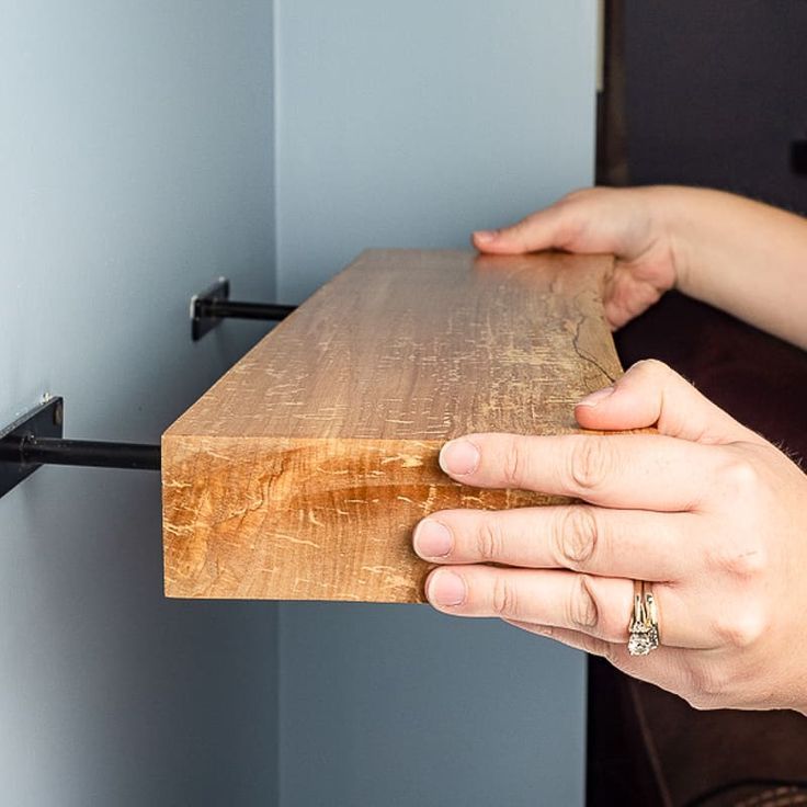 a person holding a piece of wood in their left hand with the other hand on it