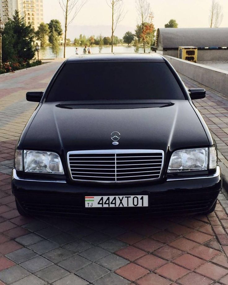 a black car parked on the side of a road next to a body of water