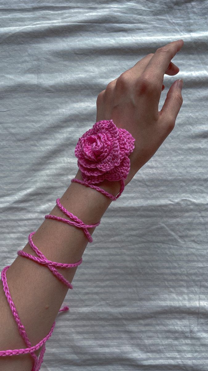 a woman's arm with pink crochet bracelets and a flower on it