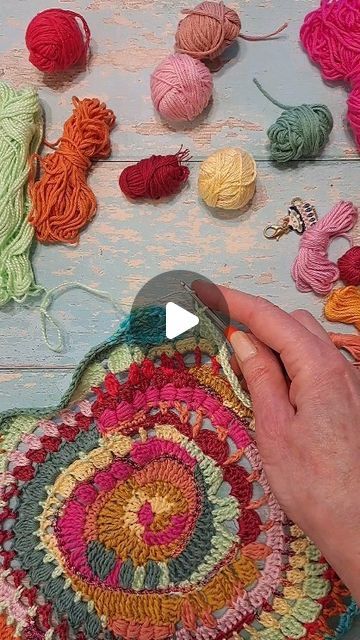 someone is crocheting together with yarn on the table next to some balls of yarn