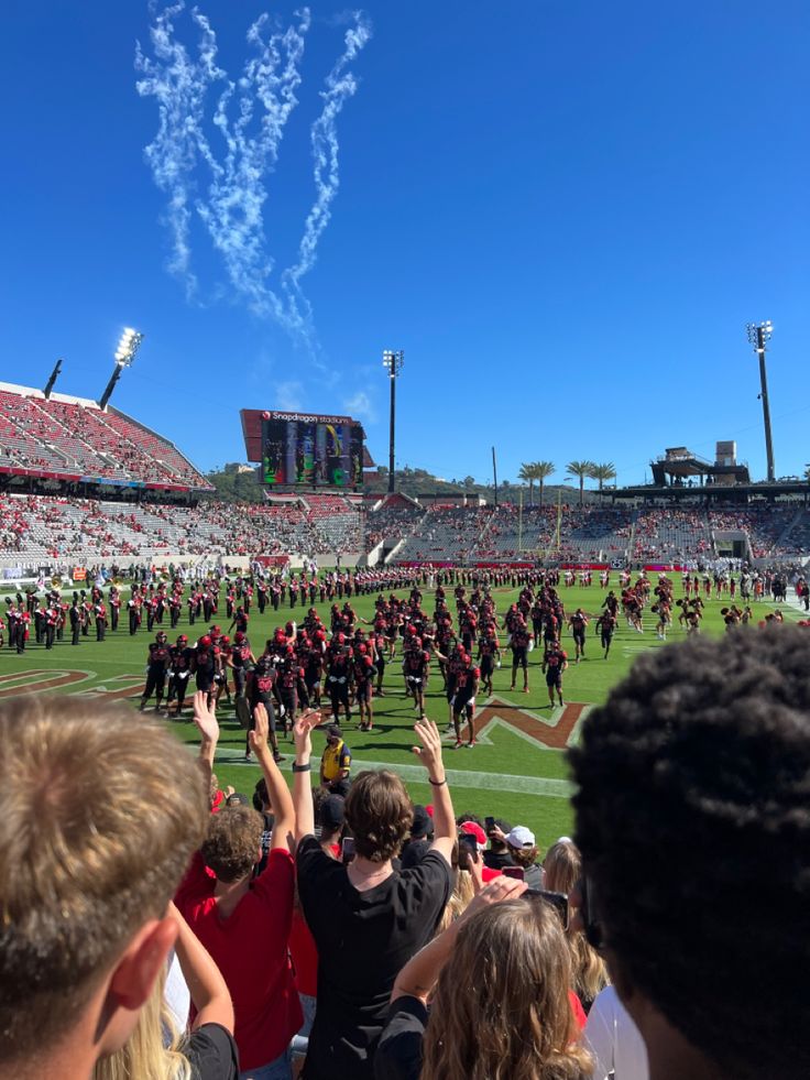 a group of people standing on top of a football field holding hands in the air