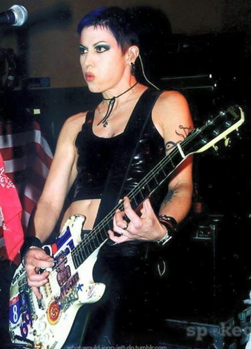 a woman with black makeup playing an electric guitar