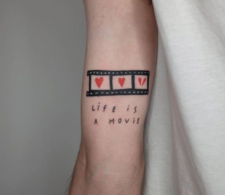 a person with a tattoo on their arm that says life is a movie and hearts