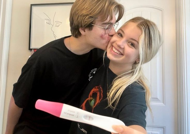 a man kissing a woman with a pink toothbrush in front of her and smiling at the camera