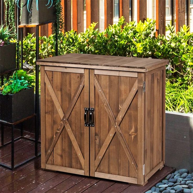 a wooden storage box sitting on top of a deck next to plants and flowers in pots