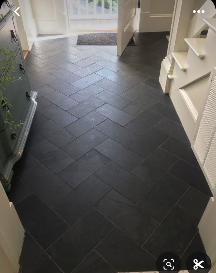 a black tile floor with white trim in a room next to a door and window