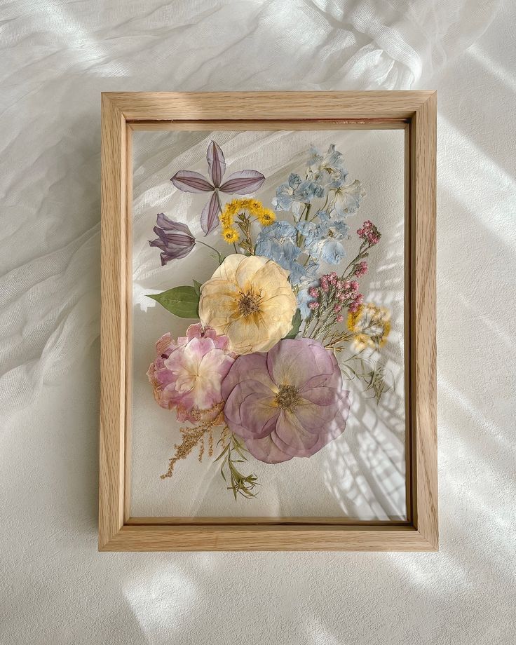 a wooden frame with flowers in it on a white sheet