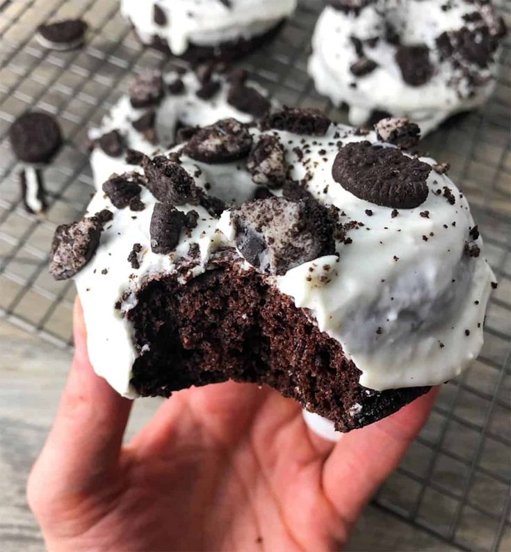 someone is holding up a chocolate cookie with white frosting and oreo cookies on top