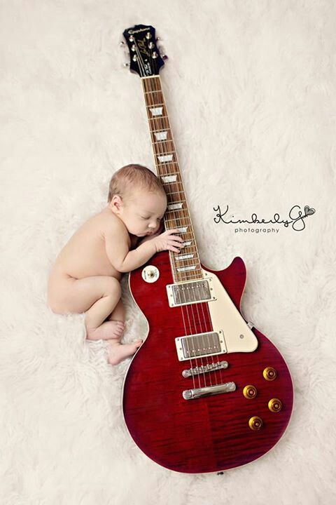 a baby laying on top of a red guitar