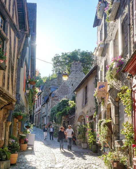 people walking down a cobblestone street in an old european town with stone buildings