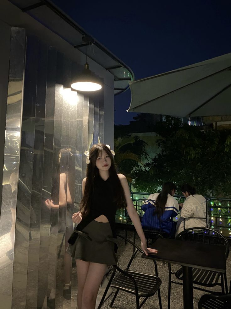 a woman standing in front of a glass wall with her hands on her hips and looking at the camera