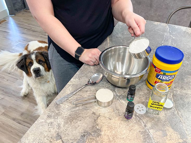 a woman standing next to a dog on top of a kitchen counter filled with cooking utensils