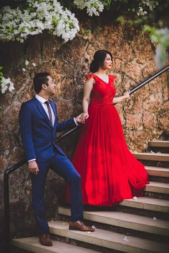 a woman in a red dress standing next to a man in a blue suit on stairs