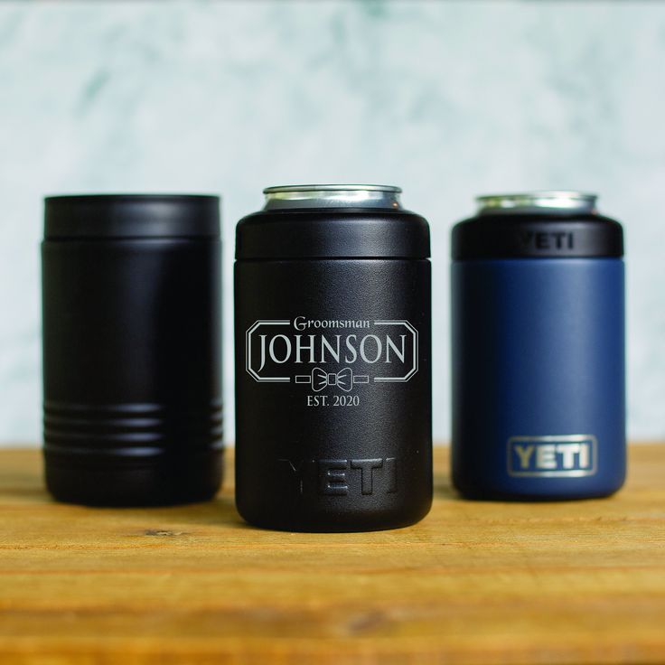 three black and blue cans sitting on top of a wooden table next to each other