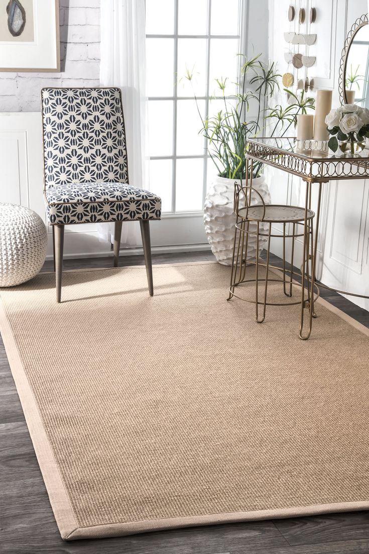 a beige rug in a living room next to a chair and table with candles on it