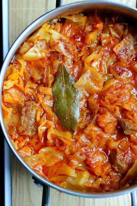 a pot filled with pasta and meat on top of a wooden table