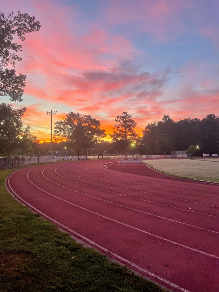 the sun is setting over an empty track