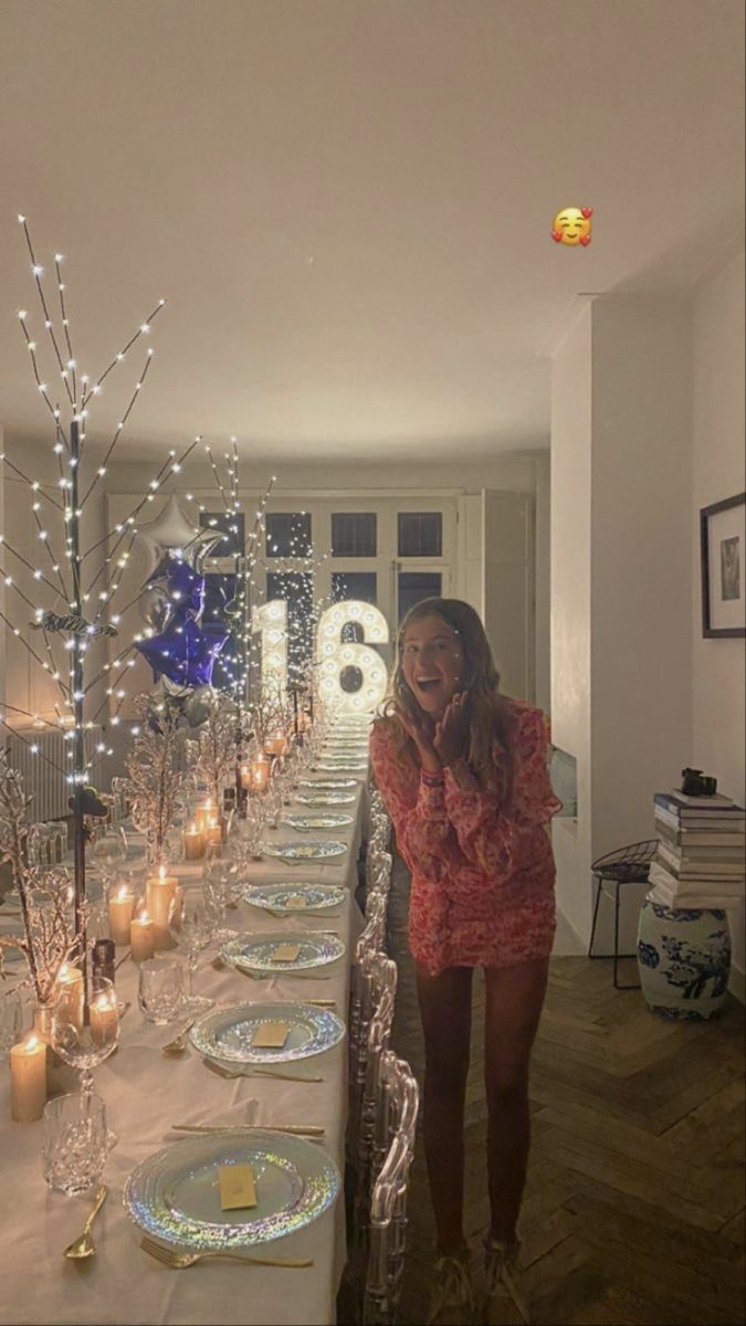 a woman standing in front of a long table with plates and candles on top of it